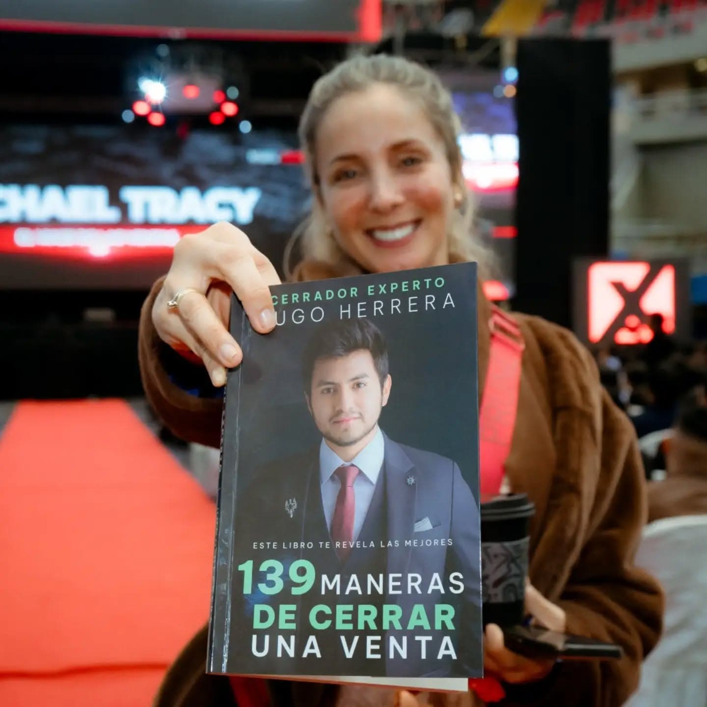 Una asistente mostrando el libro Cerrador Experto de Hugo Herrera